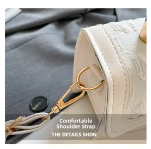 Detailed close-up of the white embossed leather surface and golden metal strap buckle