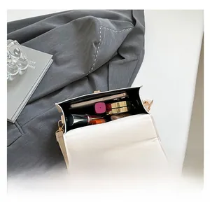 Internal capacity of white leather crossbody bag showing phone and cosmetics storage