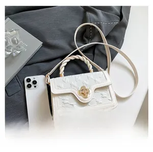 Detailed view of white embossed square bag with golden clover clasp and braided handle