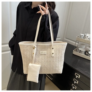 Detail of woven straw tote bag featuring contrast leather strap and matching small pouch