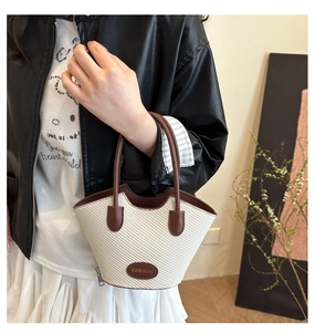 Détail du sac seau tressé avec poignées en cuir et étiquette Fashion sur le mannequin