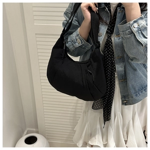 Détail d'un sac demi-lune en nylon noir montrant la bandoulière large réglable et chic