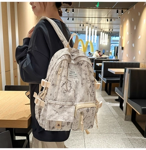 Detail of high-capacity marble print backpack with utility pockets and wide straps