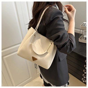 Close-up of beige leather tote bag with gold circular handle and triangular metal logo