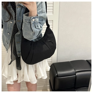 Détail d'un sac demi-lune en nylon noir avec texture plissée et bandoulière ajustable