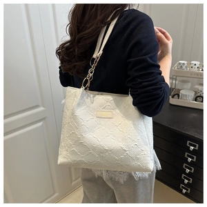 Detail of white tote bag with embossed texture and metal chain strap for commuting