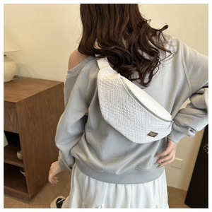 Close-up of white woven leather chest bag featuring intricate cross-weave and metal zipper