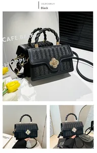 Detail of black woven crossbody bag featuring a golden clover lock and textured handle