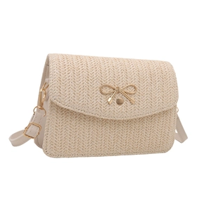 Détail du sac tissé crème avec boucle papillon dorée et texture de tissage précise