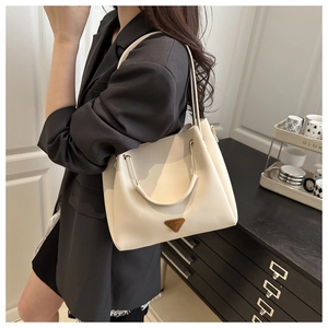 Chic cream tote bag with gold hardware and iconic triangle logo shown on shoulder