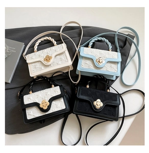 Detailed view of stylish square handbags with woven handles and floral metal buckles