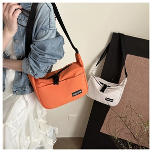 Détail de sacs bandoulière minimalistes en nylon orange et blanc avec tirettes tissées