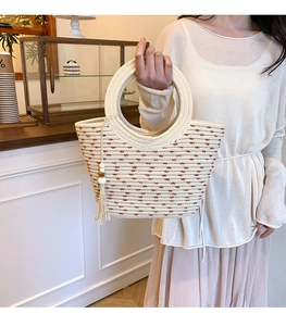 Détail du sac cabas tissé beige avec broderie à pois marrons et pompon en perles de bois