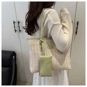 Detail of woven straw tote bag with green leather trim and fashion brand tag