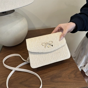 Détail de la texture tissée beige et du nœud métallique sur le sac bandoulière