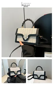 Detail of straw woven crossbody bag with black leather trim and flower metal buckle