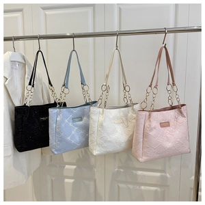 Detail of colorful canvas tote bags with metal chain straps and textured fabric patterns