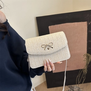 Vue détaillée du sac bandoulière en paille tressée avec boucle nœud en métal doré