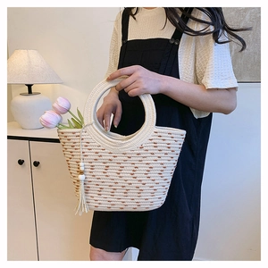 Détail du sac seau en paille avec pompon en perles de bois et texture à pois bruns