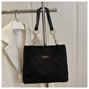 Detail of black quilted tote bag with metallic logo and gold chain shoulder strap