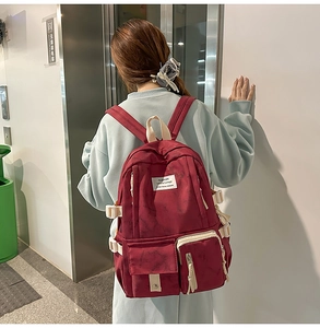 Detail of burgundy large capacity school backpack with multiple pockets and white buckles