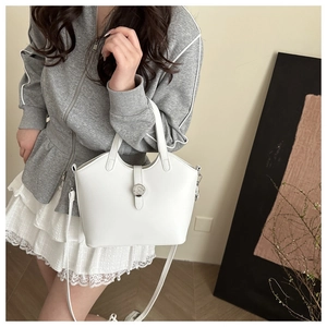 Close-up of white leather bucket bag featuring a silver logo buckle and crossbody strap