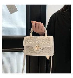 Detailed close-up of straw woven handbag with gold flower clasp and rope handle