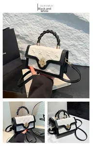 Detail view of black and white PU leather handbag with gold flower clasp and woven handle