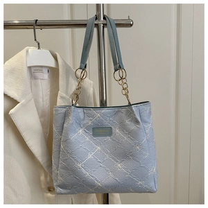 Detail of light blue tote bag with white flower embroidery and metal chain strap