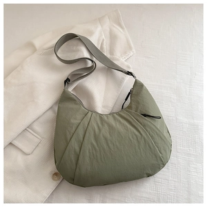Détail du sac dumpling vert olive en nylon avec bandoulière réglable et texture fine