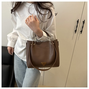 Detail shot of a dark brown matte leather tote bag with metal plaque on the front