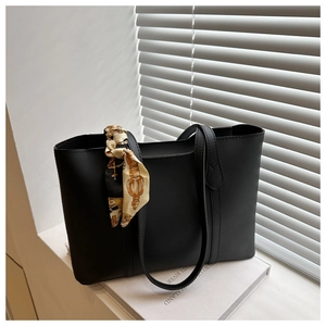 Detail of a black tote bag with printed silk scarf wrap on handle and minimal design