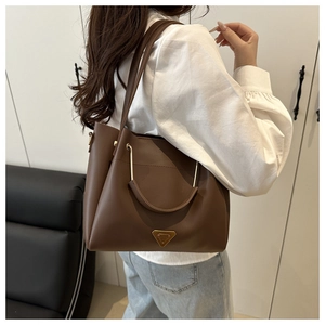 Detailed close-up of a brown leather tote bag with unique metallic curved handles