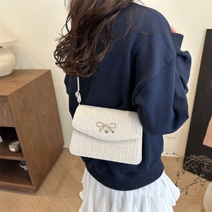 Détail du sac bandoulière tissé avec boucle en nœud doré et fine bandoulière blanche