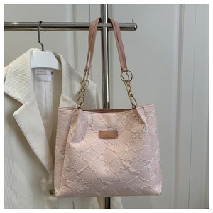 Detail of pink canvas tote bag featuring white flower embroidery and gold chain handle