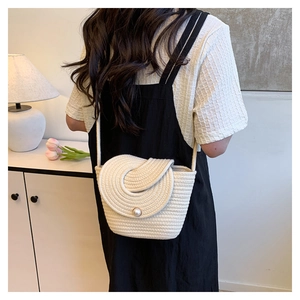 Détail du sac seau tissé beige avec fermoir perle et fine bandoulière tressée