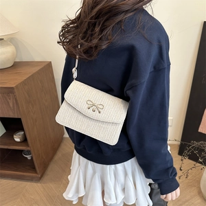 Détail du sac bandoulière tissé crème avec un fermoir boucle en métal nœud doré