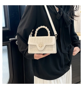 Close-up of woven straw texture with a gold flower lock on a cream crossbody bag