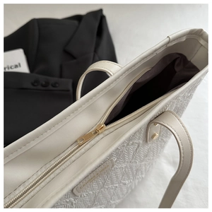 Close-up of the woven texture and metal zipper closure on the off-white tote bag
