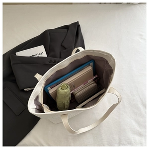 White faux leather tote bag showing large capacity with laptop and umbrella inside
