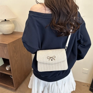 Détail d'un sac bandoulière tissé avec un nœud métallique décoratif et bandoulière blanche