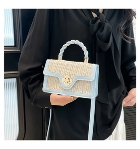 Detail of light blue straw handbag featuring a gold flower lock and woven handle