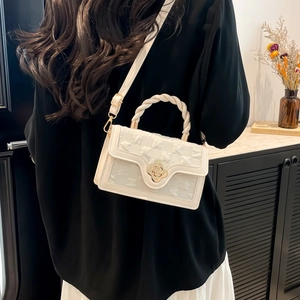 Detail of off-white crossbody bag with butterfly embossed texture and floral gold clasp