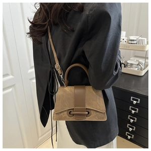 Detail of a vintage khakis suede and brown leather crossbody bag shown on a model