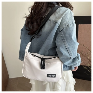 Détail du sac bandoulière en nylon blanc cassé avec sangles noires et étiquette mode