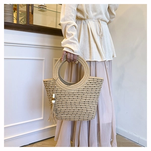 Détail du sac seau en paille avec pois noirs et pendentif à pompon décoratif