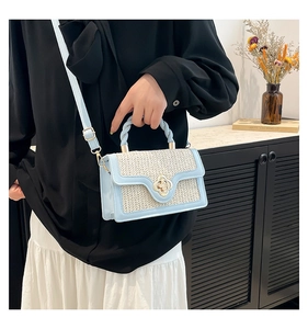 Detail of blue straw crossbody bag with floral gold clasp and woven texture finish