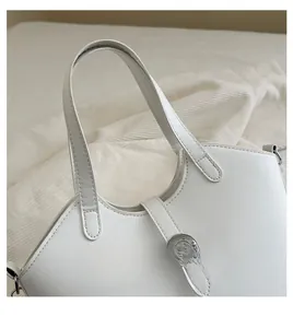 Detail view of reinforced dual handles and metal buckle on a white PU leather bucket bag