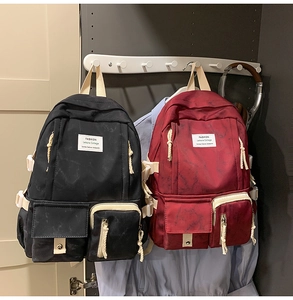 Detail of marble texture school backpacks in black and red with cream webbing straps