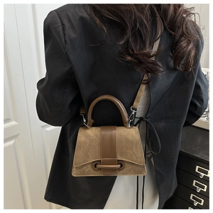Detail of vintage brown textured crossbody bag with gold ring hardware and dual materials